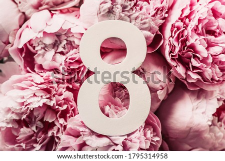 8 March. Happy Women's Day. Creative layout. Pink peony flowers and digit eight 8. Birthday greeting card. Anniversary concept. Top view. White numeral over flowers background. Numerical digit
