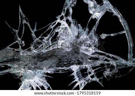 pattern from the impact of a broken mirror and glass on a black background in cracks in the form of an isolated image abstraction
