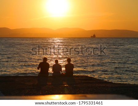 Photo landscape sunset on the sea with a group of people sitting on the shore