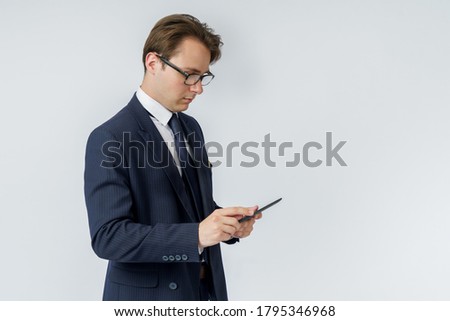 Portrait of a businessman in a blue suit holding an electronic tablet in his hands. White background. Business and finance concept
