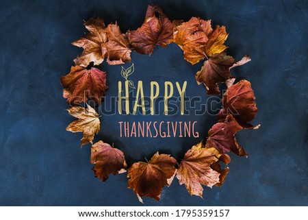 Happy thanksgiving day concept. Wreath of autumn leaves on a dark blue background with happy thanksgiving text.