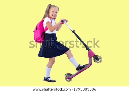 happy schoolgirl on a scooter with backpack. isolate on yellow background