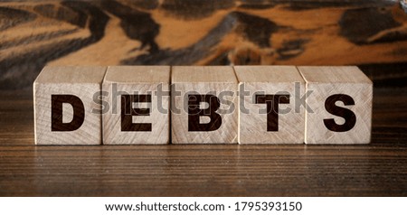 Debt wooden cubes with letters on wooden background. Financial concept.
