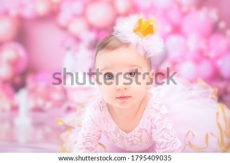 Baby girl wearing pink with birthday cake on a smash the cake photo session with pink balloons