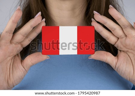 A woman shows a business card with an image of the Peru flag.
