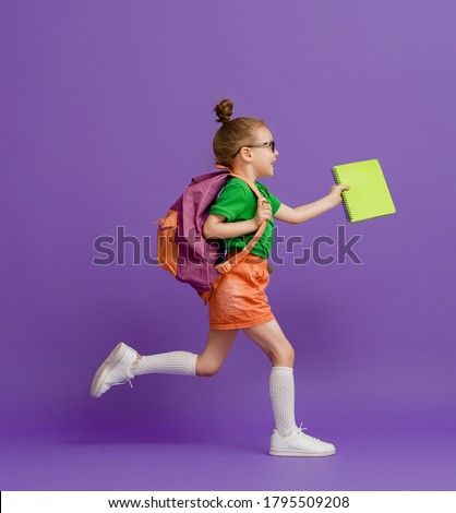 Back to school and happy time! Cute industrious child on color paper wall background. Kid with backpack. Girl ready to study. Royalty-Free Stock Photo #1795509208