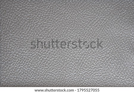 The texture of high-quality natural leather of dark color with a characteristic fine mesh pattern. Background.