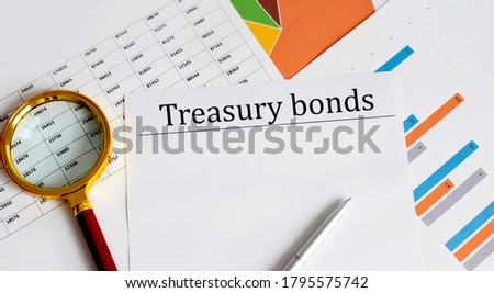 Paper with Treasury bonds on a table with charts, magnifier and pen