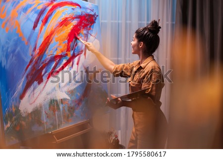 Happy fine artist painting on large canvas in art workshop. Modern artwork paint on canvas, creative, contemporary and successful fine art artist drawing masterpiece