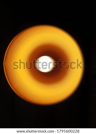 Blurred images of orange light from the lamp inside a circular lamp hanging on the ceiling. Electric bulb's bottom view on a solid black background The concept of light in the dark