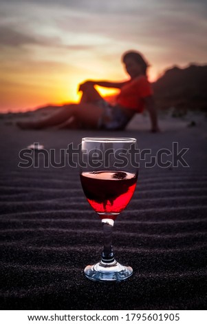a glass of wine on beautiful sunset with blurred the girl in background, selective focus technique