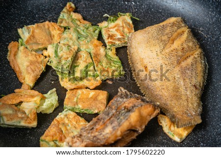 deep fried fish and Fried Egg with Climbing Wattle in the pan