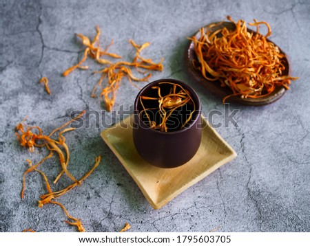 Dried cordyceps militaris mushroom with cup. cup of cordyceps (chong cao) tea on old and crack wooden surface, Healthy beverage concept. chinese herb.