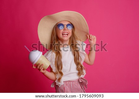 a little girl traveler in sunglasses with a can of cocktail smiles on a pink background