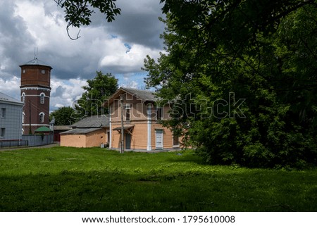 cityscape with green trees in summer with old houses against blue sky