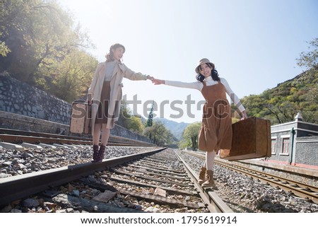 Young girlfriends go hand in hand on the rail