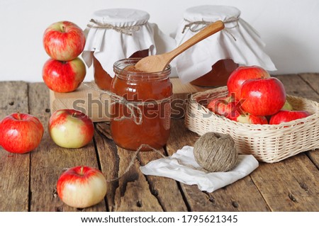 Homemade jams for future use.Amber apple jam in jars on a wooden rustic table with a white background.