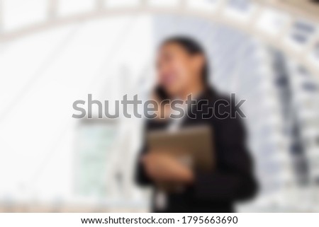 Business blur concept : Blurred young woman holding talking on the phone working with documents at the town, 