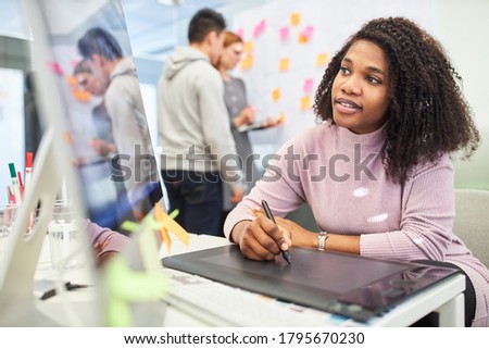 African woman as a graphic designer uses the pen to design a layout on a tablet computer