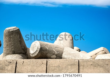Close -up picture of the parts of concrete tetrapods for coastal protection from breakwaters. At the background blue sky.