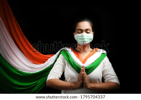 Independence Day (15 august) - happy Indian women in Indian attire with  national Indian flag, wearing tricolor cloths and mask on. Royalty-Free Stock Photo #1795704337