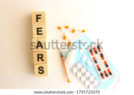 The words FEARS is made of wooden cubes on a white background with medical drugs and medical mask. Medical concept.