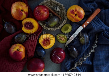 Top view photo of beautiful fresh fruits on a table. Red and blue textured background. Vibrant colors of juicy plums and nectarines. 