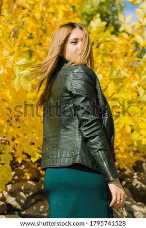 Portrait of a young blonde of European descent in a black jacket, against a background of yellow leaves. Young woman in the autumn forest.Photo taken in October