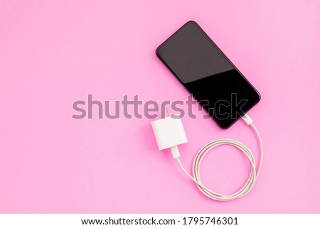 Top view new smartphone with white charger on color background with copy space for text or design
