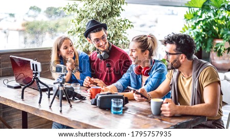 Digital native friends sharing feed on streaming platform with phone and web cam - Content marketing concept with millenial workers having fun vlogging live video on social media space - Bright filter Royalty-Free Stock Photo #1795757935