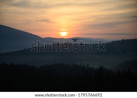 Silhouette Drone flying on mountain sunrise sky with cloud, Aerial photography. mountains landscape with sun and alpine pines. Sunrise