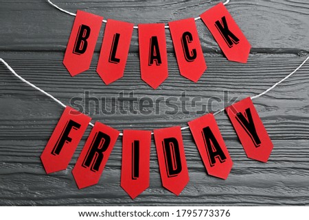 Words BLACK FRIDAY made with red tags on dark wooden background, flat lay