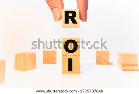 The text roi man holds a wooden cube. Business concept