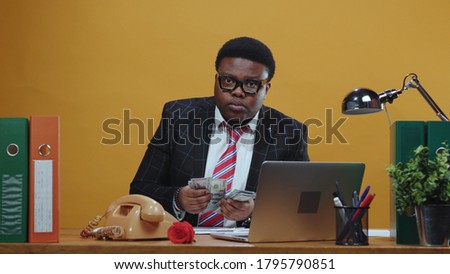 African businessman company leader carefully checks his salary counting money and looking around to not be spied. Jealous boss. Business people. Copy space.