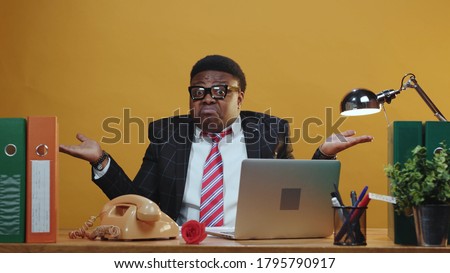 Handsome dark-skinned office manager reading paper report shrugging shoulders in hesitation doubting at camera working in company corporation. Expressions. Copy space. Royalty-Free Stock Photo #1795790917