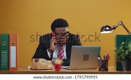 Smart attentive afro-american executive talks on telephone call solving business tasks problem using smartphone device calling at modern office corporation.