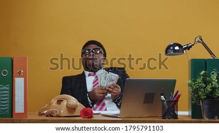 Happy satisfied african leader businessman counts money banknotes on payday sitting relaxed in boss chair at modern office company. Successful people. Copy space.