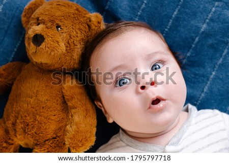 Surprised baby with toy on blue background top view