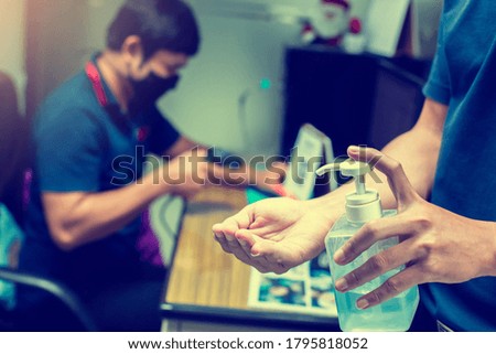 Washing hands with alcohol sanitizer to avoid contaminating with Coronavirus Covid-19. Washing hand with blurry business man in meeting room. The concept of cleaning in office to protect Covid 19.