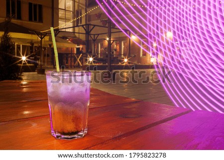 Glass with a cocktail with a straw, outside, toned photo.