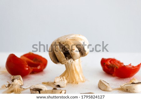 Cut white mushroom and cherry tomatoes in the background.