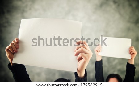 Two women holding blank paper above their heads