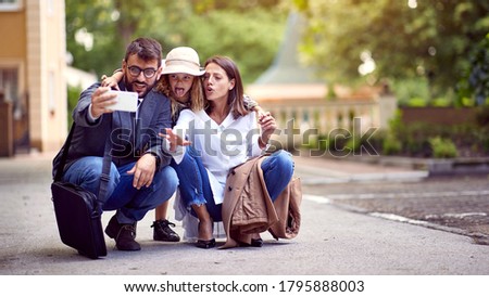 Parents taking family selfie with daughter after school