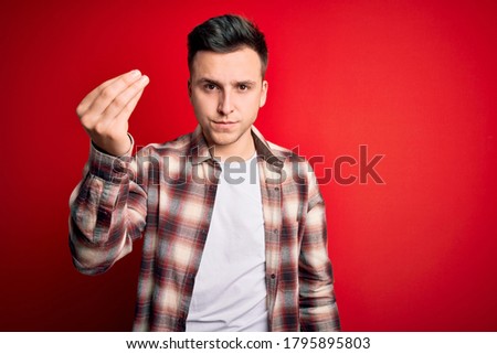 Young handsome caucasian man wearing casual modern shirt over red isolated background Doing Italian gesture with hand and fingers confident expression