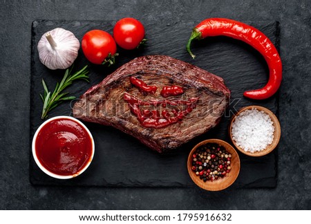 
Grilled beef monster steak with spices for halloween on stone background