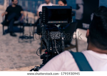 Behind the scene concept. Cameraman working on professional camera taking film interviewer interview celebrity people making news outdoors.