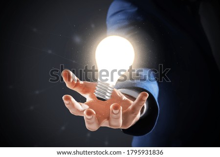 Idea concept. Businessman demonstrating glowing light bulb illustration on dark background, closeup
