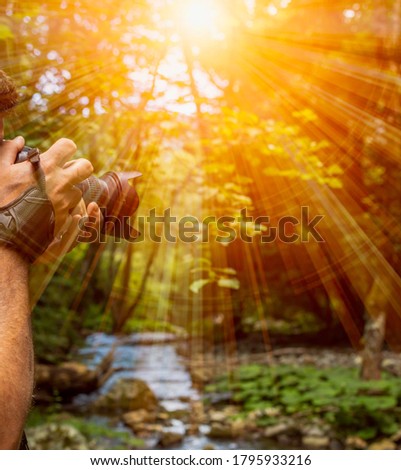 Close Up of a Photographer taking a Photo in the forest with a river and lens flare. Mystical atmofphere