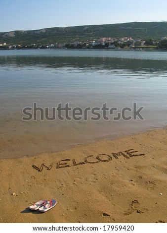 Empty piece of beach with welcome sign written in sand