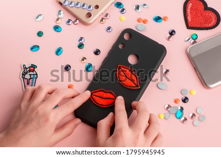 Girl putting red lips patches on black phone case. Cool way to style up a simple phone accessory. Gadgets and custom design.